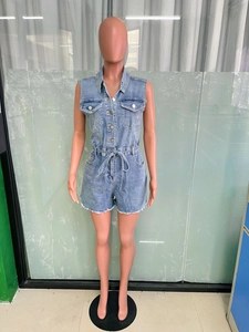 Détail d'un combishort en jean bleu clair avec boutons en métal, cordon et ourlet effiloché