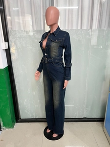 Detail view of denim jumpsuit featuring metal buttons and adjustable buckled waist belt