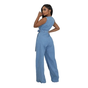 Side view of model wearing a light blue denim sleeveless jumpsuit with tied waist