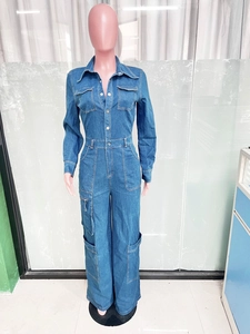 Detail of blue denim jumpsuit featuring utility pockets and metallic zipper accents