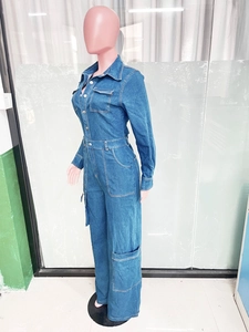 Detail of blue wash denim jumpsuit showing long sleeves and utility cargo side pockets