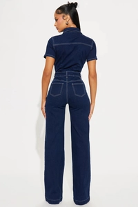 Detail view of the back of a deep blue denim jumpsuit with white stitching and pockets
