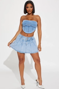Détail d'un ensemble deux pièces en jean bleu avec haut corset et mini-jupe plissée