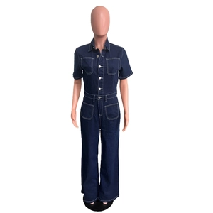 Detail view of dark blue denim jumpsuit featuring white contrast stitching and metal buttons
