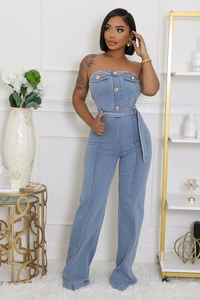 Dettaglio della tuta in denim azzurro senza spalline con bottoni dorati e cintura in vita