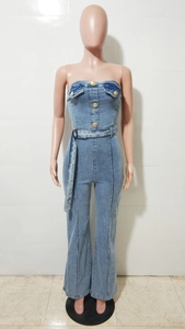 Dettaglio tuta di jeans azzurra senza spalline con bottoni dorati e cintura coordinata