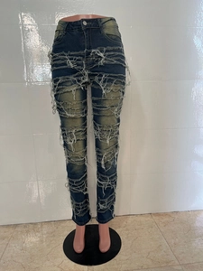 Gros plan sur un jean denim usé avec des déchirures à franges et détails effilochés