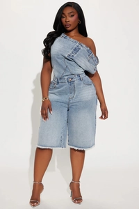 Détail d'un combishort en jean bleu clair avec épaule asymétrique et bords effilochés