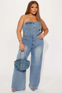 Detail eines blauen Jeans-Jumpsuits mit Taillenausschnitten und Sternen-Handtasche