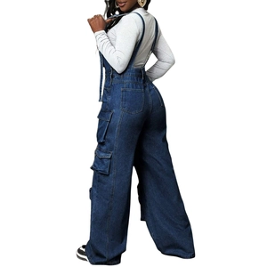 Side-back view of wide-leg denim dungarees featuring utility flap pockets and metal buckles
