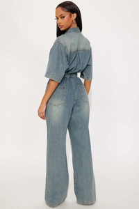 Detail view of light blue denim jumpsuit featuring elastic waist and wide leg cut