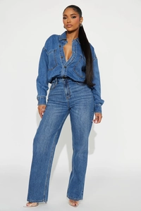 Detail view of washed blue denim fabric texture and stitching on long sleeve jumpsuit