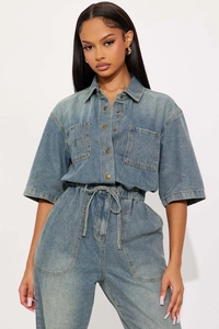Detail of light blue washed denim jumpsuit with short sleeves and cargo pockets