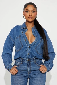 Close-up of blue wash denim jumpsuit showing metal buttons and utility pockets detail