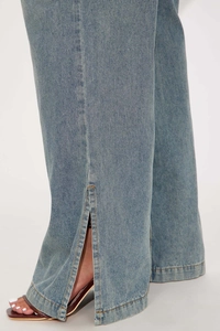 Detail of light blue denim flared jumpsuit with side split hem and contrast stitching