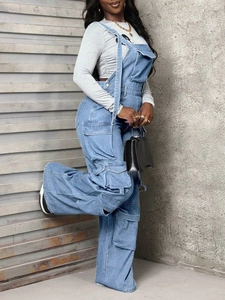 Macro detail of baggy denim overalls featuring side cargo pockets and washed blue fabric texture