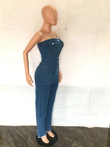 Detail of blue denim strapless jumpsuit featuring metal buttons and raw hem edges