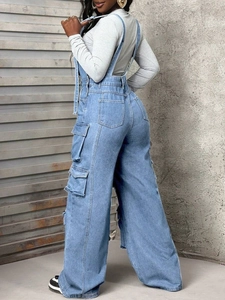 Detail view of cargo pockets on blue denim overalls from a side angle