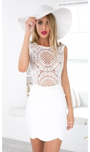 Detail of white sleeveless dress showing intricate lace embroidery and scalloped hemline