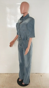 Detail of blue-grey wash denim jumpsuit featuring waist drawstring and side split leg