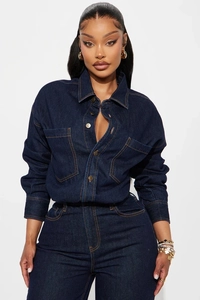 Detail of slim fit denim jumpsuit featuring bronze buttons and contrast stitching