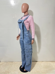 Detail of light blue denim overalls with side pockets and a pink patterned mock neck top