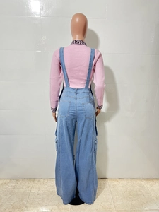Detail view of high-waist light blue denim overalls with large cargo pockets and retro pattern