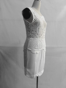 Detail of white sleeveless dress showing intricate floral crochet lace and hollow patterns