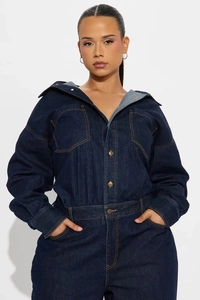 Detail of dark blue denim jumpsuit with long sleeves, vintage metal buttons, and flap pockets