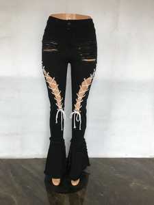 Detail der schwarzen Schlagjeans mit Distressed-Cuts und weißem Kreuzbandagen-Design