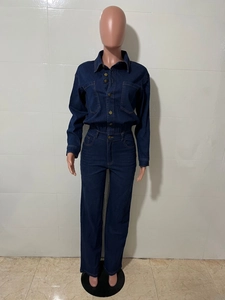 Detail of dark blue denim jumpsuit with metal buttons and slim waist on a mannequin