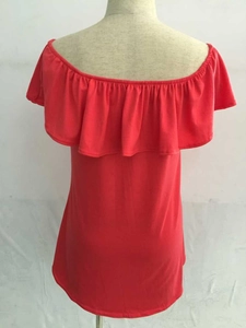 Détail d'une robe en maille rouge à épaules dénudées avec décolleté à volants et texture
