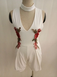 Detailed view of white off-shoulder romper with red rose floral embroidery on the waist