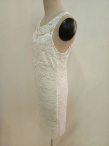 Dettaglio dell'abito bianco senza maniche con pizzo traforato e raffinati motivi floreali