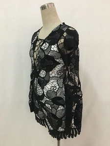Detail of the plunging V-neck with lace-up ties and floral hollow lace fabric on black romper