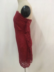 Dettaglio del pizzo floreale rosso scuro e dell'orlo dell'abito aderente ed elegante