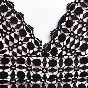 Détail macro de dentelle florale noire avec doublure rose sur une robe moulante