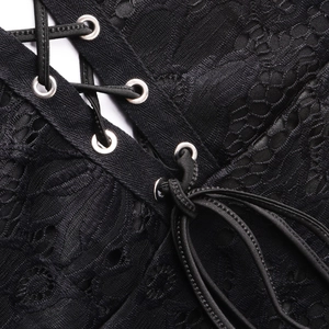 Makro-Detail der Blumen-Spitze mit Metallösen und schwarzen Schnürbändern am Kleid