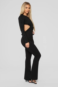 Detail eines schwarzen Jumpsuits mit Seitenausschnitten und Perlenverzierung