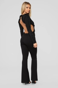 Detail der rückenfreien Aussparung mit Perlenbesatz am schwarzen langärmeligen Jumpsuit