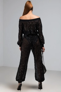 Vue arrière d'une combinaison noire à paillettes avec manches lanternes et motifs carreaux