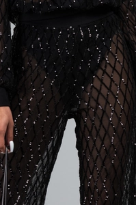 Gros plan du pantalon en mesh noir avec sequins à motif losange et effet de transparence