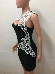 Détail de l'applique en dentelle florale sur une robe moulante noire avec broderie blanche