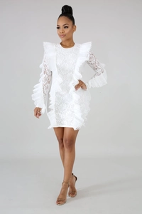 Dettaglio dell'abito in pizzo bianco con ricami floreali e balze accentuate sulle spalle