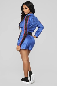 Detailweergave van de contraststrepen op de blauwe set met ritsjasje en korte broek