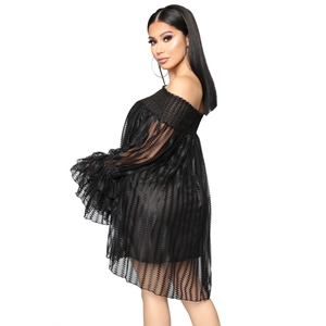 Détail d'une robe en maille noire à épaules dénudées avec des volants et texture ondulée