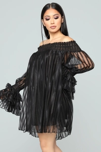 Détail d'une mini-robe noire à épaules dénudées avec volants et texture ondulée