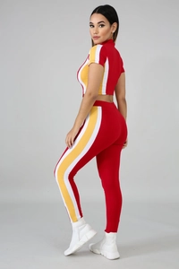 Detail of red athletic crop top and leggings with yellow side stripes on studio model