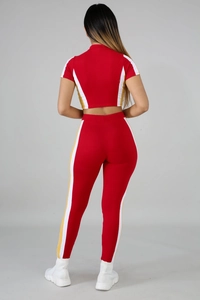 Detail view of the high-stretch knitted back of a red two-piece tracksuit with side stripes
