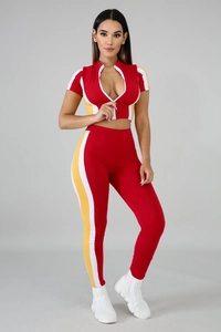 Detail of red athletic two-piece set featuring contrast side stripes and zipper crop top
